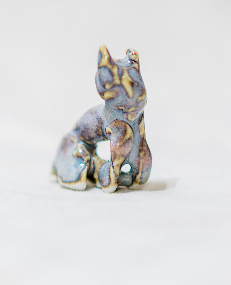 close up of Adeline Fields' porcelain cat with multi-blue red and tan glaze