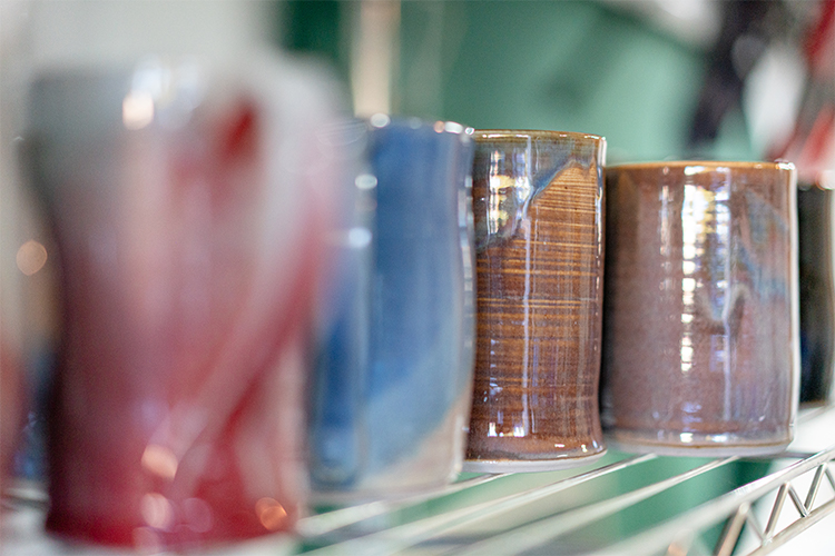 close of of stoneware cup collection on studio shelf of potter Converse Fields