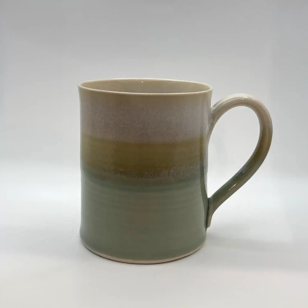 coffee mug ceramic handmade color is variegated shades of celadon to pink hand thrown by Converse Fields Pottery in Terrebonne Oregon
